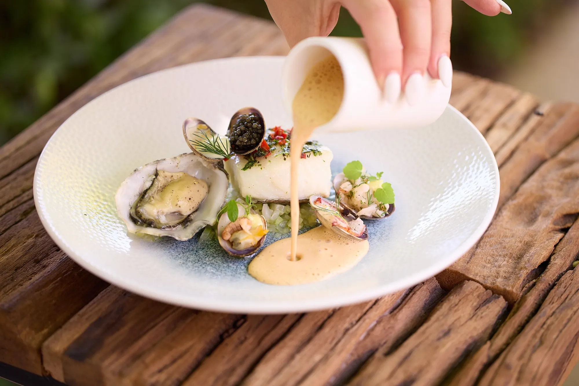Oesters en schelpdieren met een saus die aan tafel wordt overgoten